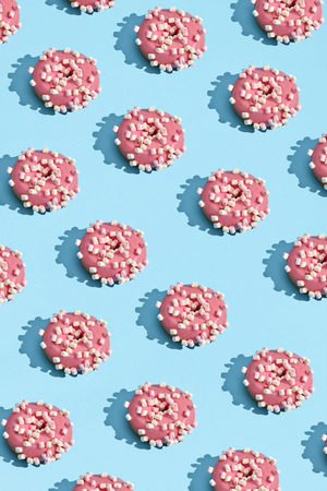 Food design with tasty pink glazed donut on blue pastel background top view patternの写真素材