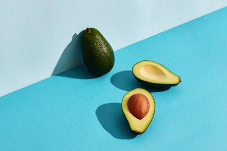 Composition of fresh fruits, whole avocado and two halfs of cutted avocadoの写真素材
