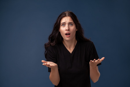Portrait of a long-haired brunette woman in black t-shirt posing on a gray background and showing different emotions.の写真素材
