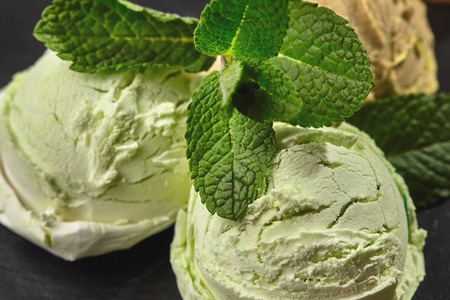 Gourmet chocolate and pistachio ice cream served on a stone slate over a black background.の写真素材