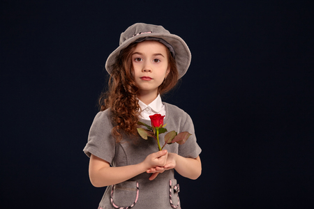 Studio shot of a lovely little kid with a long, curly hair posing on a black background.の写真素材