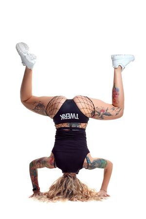 Sexy blond twerk woman with tattoed body and long curly hair is posing in studio.の写真素材