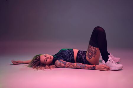 beautiful caucasian blonde girl in velour blue booty shorts and black stockings does exercises on pink backgroundの写真素材