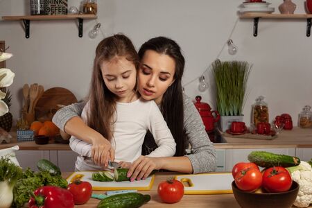 Mother and her daughter are making a vegetable salad and having fun at the kitchen.の写真素材