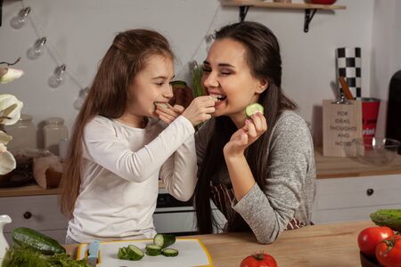 Mother and her daughter are making a vegetable salad and having fun at the kitchen.の写真素材