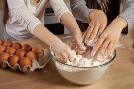 Mother and her daughter are baking a bread and having fun at the kitchen.の写真素材