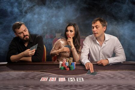 Group of a young rich friends are playing poker in casino.
