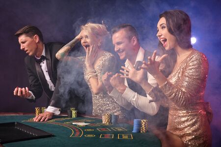 Group of a stylish rich friends are playing poker at casino.