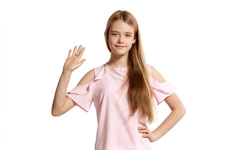 Studio portrait of a beautiful girl blonde teenager in a pink t-shirt posing isolated on white background.の写真素材