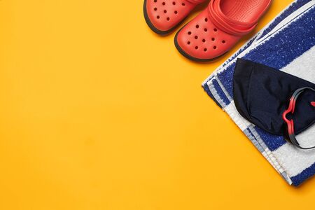 Flat lay summer pool accessories on a yellow background. Colorful beach wear.