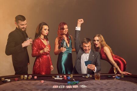 Group of a young wealthy friends are playing poker at a casino.