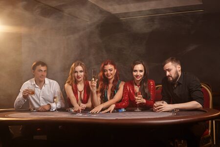 Group of a young wealthy friends are playing poker at a casino.