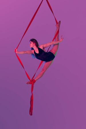 Beautiful girl in a black swimsuit is performing an acrobatic elements in studio.の写真素材