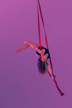 Beautiful girl in a black swimsuit is performing an acrobatic elements in studio.の写真素材