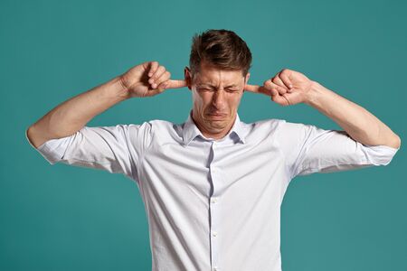 Portrait of a young brunet man posing in a studio against a blue background.の写真素材