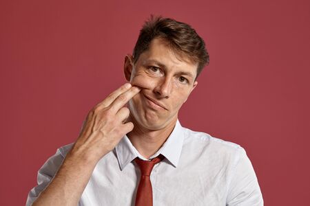 Portrait of a young brunet man posing in a studio against a red background.の写真素材