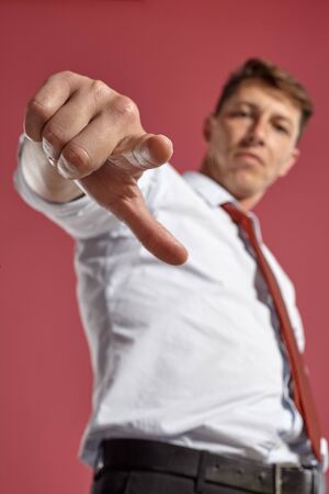 Portrait of a young brunet man posing in a studio against a red background.