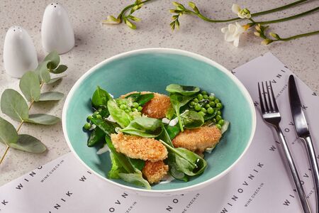 Fried breaded crispy chicken slices in a blue plate served on a table with a white tablecloth.の写真素材