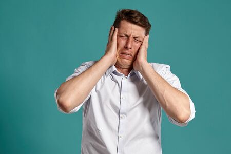 Young man in a classic white shirt is posing over a blue background.の写真素材