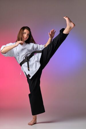 Athletic woman in traditional kimono is practicing karate in studio.の写真素材