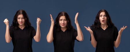 Beautiful woman in a black casual t-shirt posing against a blue studio background.の写真素材