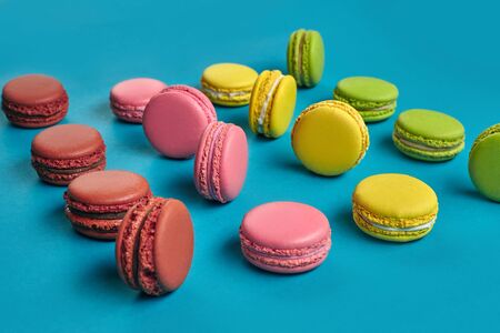 Colored macaron or macaroon, sweet meringue-based confection on blue background. Close-up, copy...