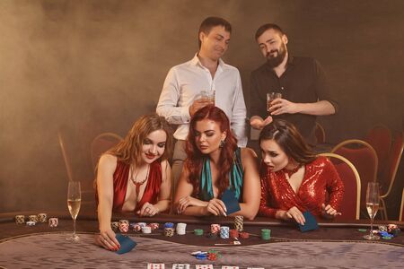 Group of a young wealthy friends are playing poker at a casino.