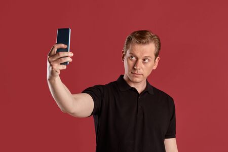 Close-up portrait of a ginger guy in black t-shirt posing on pink background. Sincere emotions.の写真素材