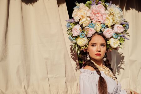 Brunette girl in a white ukrainian authentic national costume and a wreath of flowers is posing...