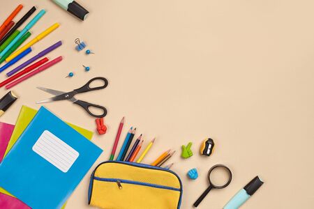 Flat lay photo of workspace desk with school accessories or office supplies on pink background.