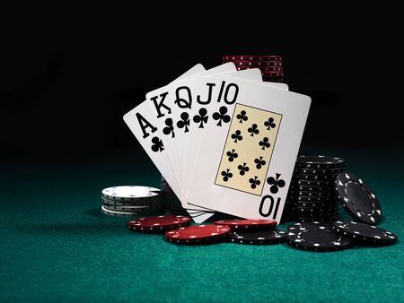 Royal flush standing leaning on colorful chips piles on green cover of playing table. Black background. Close-up.の写真素材