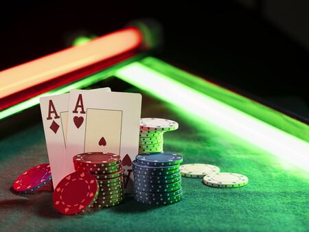 Two aces standing leaning on chips piles, some of them laying nearby on green cover of playing...