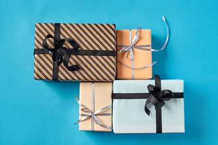 Different sizes, colorful, striped and plain, brown, pink and white paper present packages tied with...