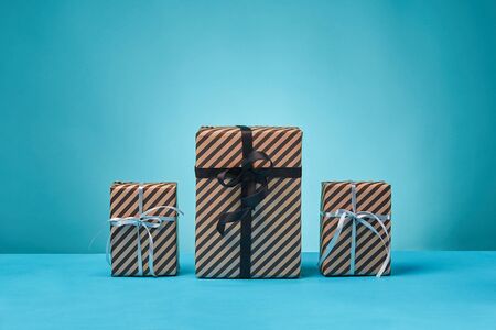 Present packages tied with black and silver ribbons and bows on a blue surface