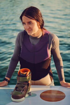 Brunette girl in a gray turtleneck with her wakeboard