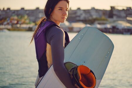 Brunette girl in a gray turtleneck with her wakeboard