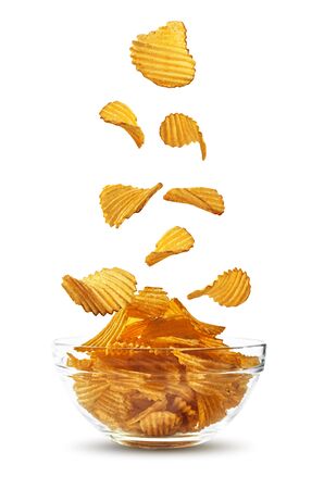 Grooved potato crisps falling down in glass bowl, isolated on white background with copy space for text, images. Crispy chips. Advertising. Close-up.の写真素材