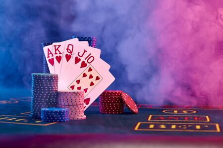 Winning combination in poker leaning on colored chips piles on blue cover of playing table. Black,...