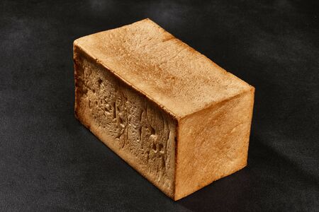Whole loaf of fresh, delicious baked white bread against black