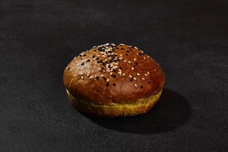 Fresh, baked, green bun sprinkled with sesame seeds against blackの写真素材