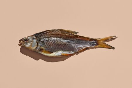 One jerky or dried salty roach, delicious clipfish on pink background. Famous beer appetizer. Traditional way of preserving fish. Close up, copy space, top viewの写真素材