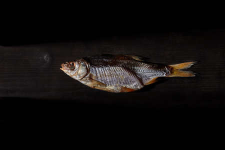 One dried or jerky salted taranka, yummy clipfish on wooden background. Salty beer snack....
