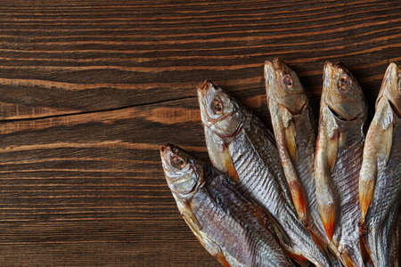 Dried or jerky salted roach, clipfish on wooden background. Salty beer appetizer. Traditional way of...