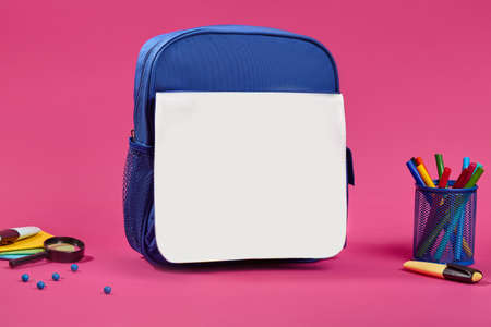 Blue and white school bag, colorful felt-tip pens in a stand, blue pins, magnifying glass and pencil...