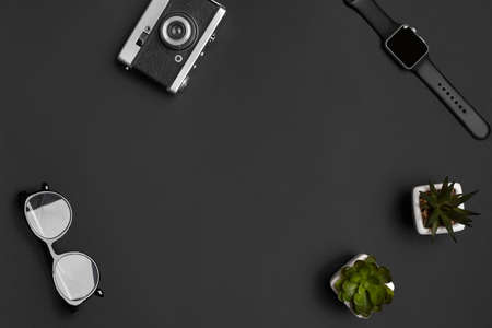 Old vintage camera, glasses, smartwatch and two green succulents in white pots on black studio background. Modern technology. Close up, copy spaceの写真素材