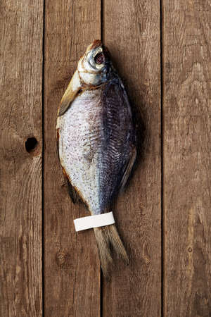 Air-dried silver bream with label on tail on rough wooden surfaceの写真素材