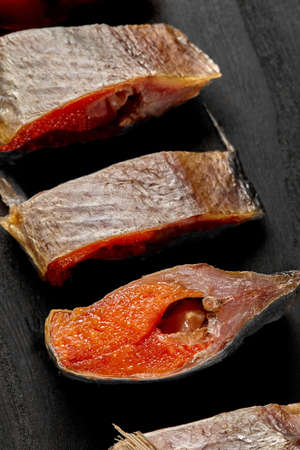 Sices of salted air-dried roach with roe on black wooden surfaceの写真素材