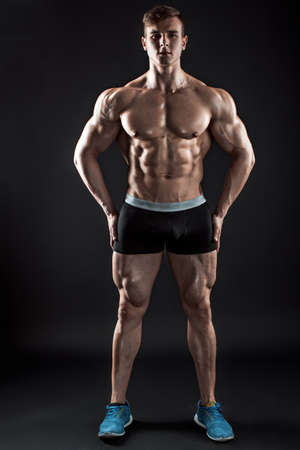 Muscular bodybuilder guy doing posing over black backgroundの写真素材