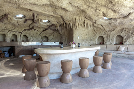 Patio in artificial rocky cave with marble table, wooden chairs, sofa and kitchen cabinetsの写真素材