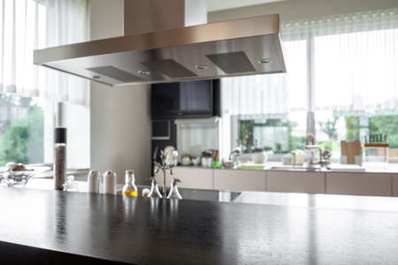 Black wooden countertop with bottles of condiments on blurred kitchen backgroundの写真素材